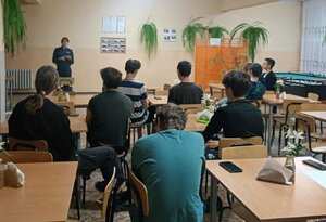 Policjantka stoi i mówi do siedzącej młodzieży