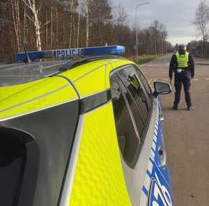 Policjant stoi przed radiowozem