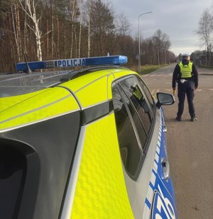 Policjant stoi przy drodze przed radiowozem