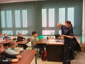 Policjanci stoją, dzieci siedzą i słuchają