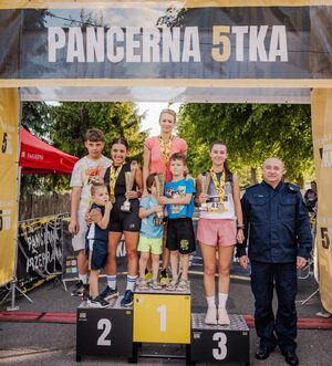Zdjęcie przedstawia zawodników na podium II Podkarpackich Mistrzostw Policji w biegu ulicznym na 5 km.