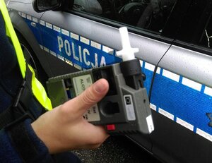 Zdjęcie przedstawia urządzenie do badania trzeźwości kierujących oraz radiowóz
