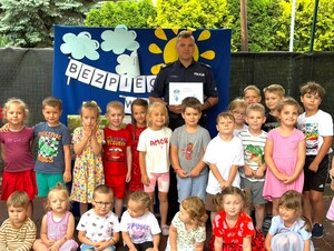 Na zdjęciu widoczny jest dzielnicowy i dzieci uczestniczące w spotkaniu